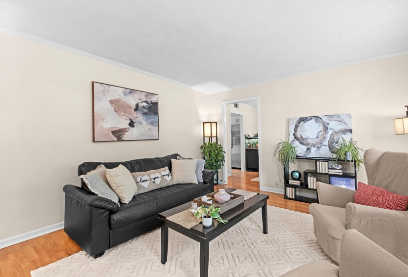 Living area featuring wood-finish flooring, light neutral wall tones, and crown molding