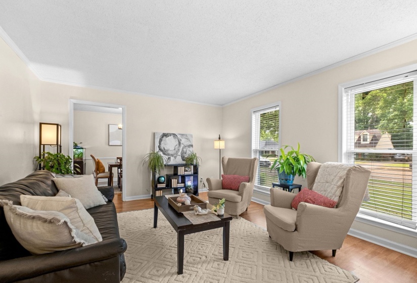 Living area featuring wood-finish flooring, light-toned walls, and white crown molding