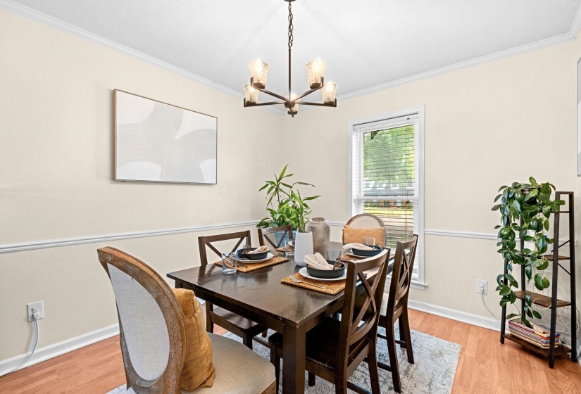 Dining area featuring wood-finish flooring, a contemporary chandelier, and a window with blinds