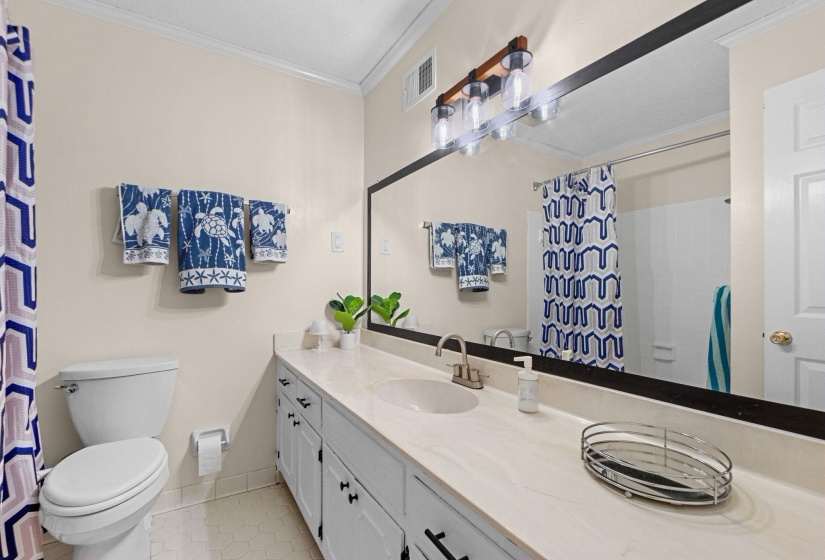 Bathroom vanity featuring a single basin sink, light-toned countertop, and white cabinetry with dark hardware