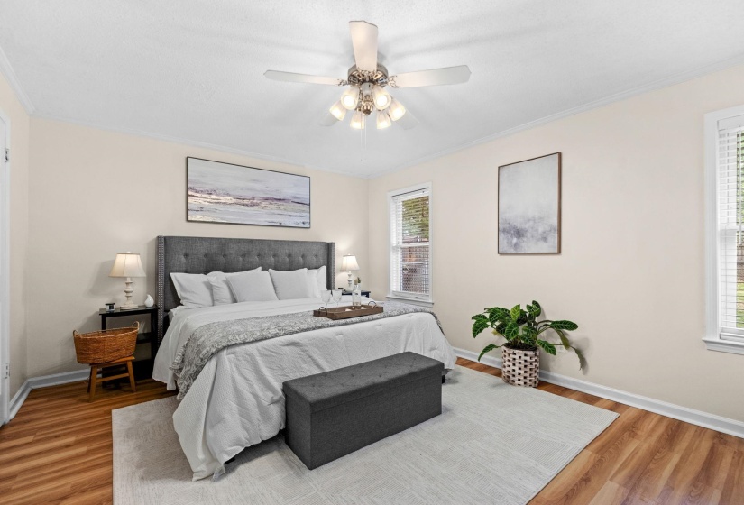 Bedroom featuring wood-finish flooring, light-toned walls, crown molding, and two windows with blinds