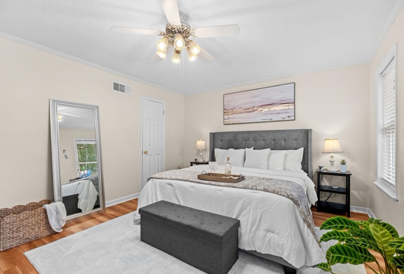 Bedroom featuring wood-finish flooring, a ceiling fan with integrated lighting, crown molding, and a window with blinds