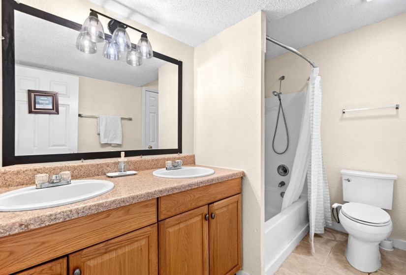 Bathroom featuring a double vanity with light wood cabinetry, a speckled countertop, and two undermount sinks