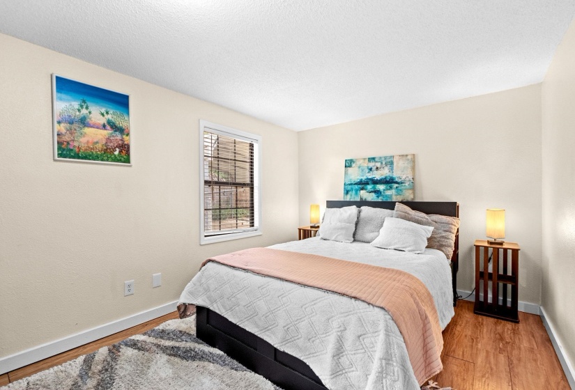 Bedroom featuring wood-finish flooring, white baseboards, and a window with blinds