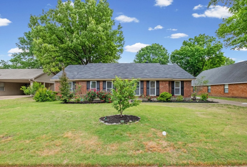 Brick exterior with a dark-shingle roof, featuring white-framed windows with black shutters