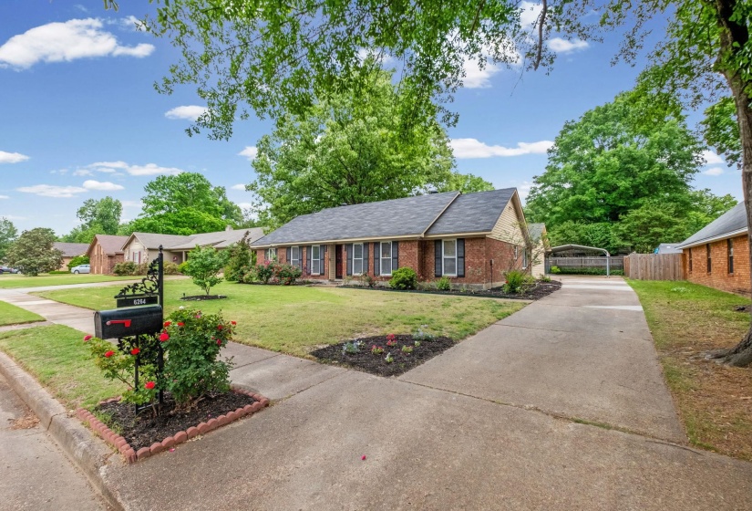 Traditional brick facade residence with dark shutters and a dark shingle roof