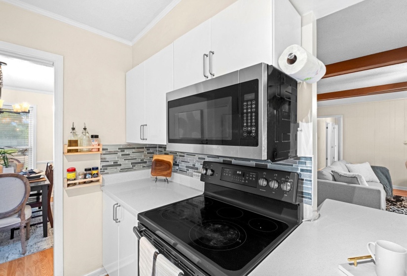 Modern kitchen featuring white cabinetry, a stainless steel over-the-range microwave, and a black electric range with a flat cooktop