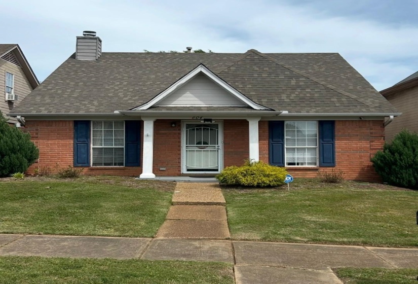 Brick exterior featuring a gabled entry with white columns and a front door with security screen
