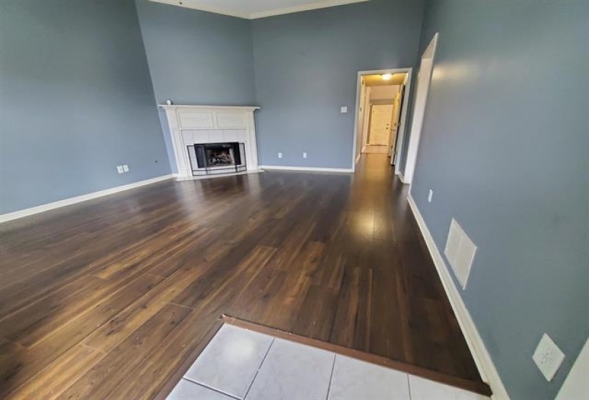 Living area featuring high ceilings, wood-finish flooring, a white mantel fireplace, and light blue wall tones