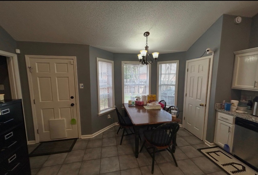 Kitchen eating area featuring a bay window, tiled flooring, and a multi-light chandelier