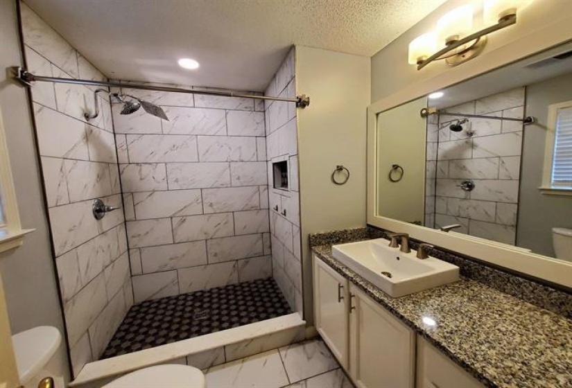 Modern bathroom featuring a walk-in shower with large format tile walls and a hexagonal tile floor