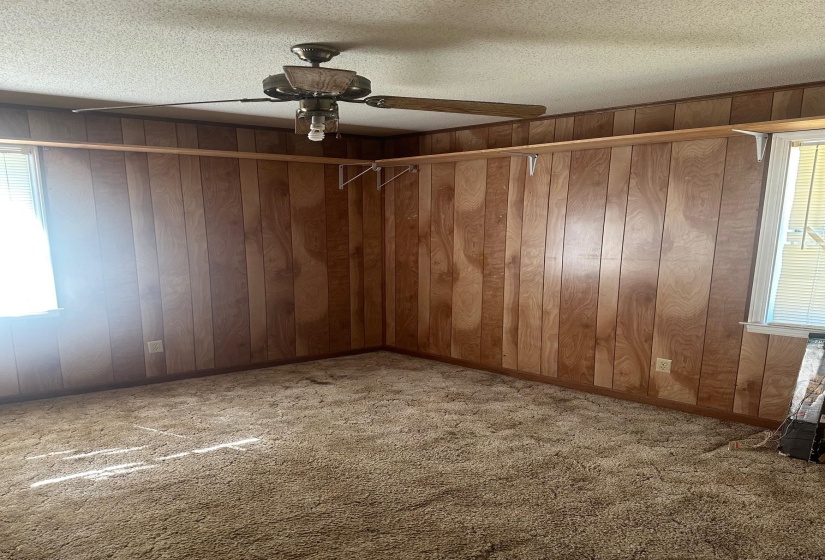 Room featuring wood paneling, a ceiling fan with integrated lighting, and wall-mounted shelving
