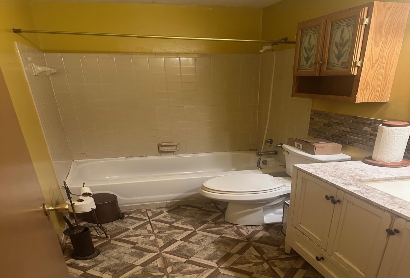 Bathroom featuring a white bathtub, ceramic tile shower surround, and patterned flooring