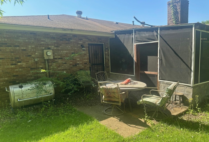 Brick exterior featuring a screened-in porch with a concrete patio