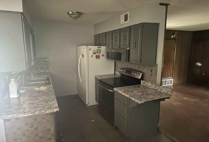 Kitchen featuring grey cabinetry, speckled countertops, a double basin sink, and wood-finish flooring