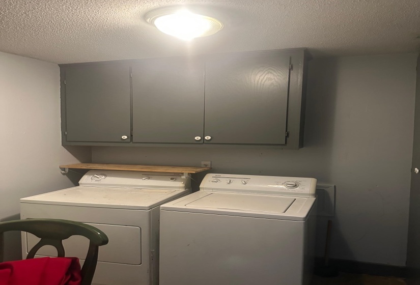 Laundry area featuring gray cabinetry with white knob hardware, a wooden shelf, and a ceiling-mounted flush light fixture