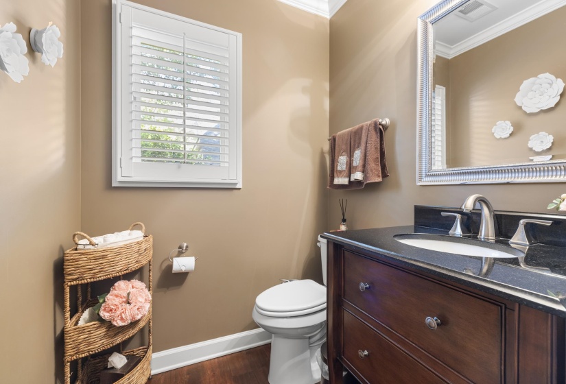Half bath located next to kitchen 1st floor Bathroom featuring a dark wood-finish vanity with a dark countertop and undermount sink, brushed nickel faucet, and a large framed mirror