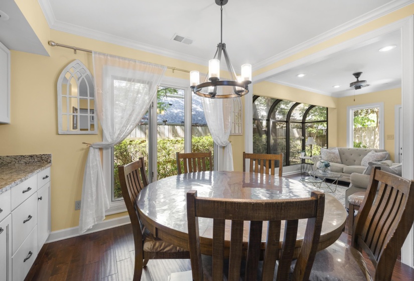 Dining area with wood-finish flooring, white cabinetry, and granite countertops