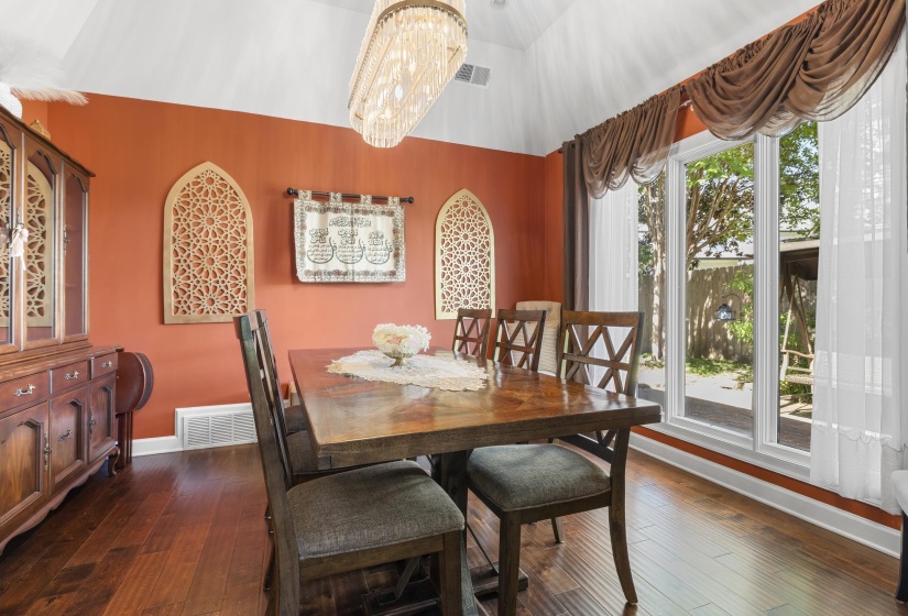 Dining area featuring wood-finish flooring, a large multi-pane window, and a vaulted ceiling