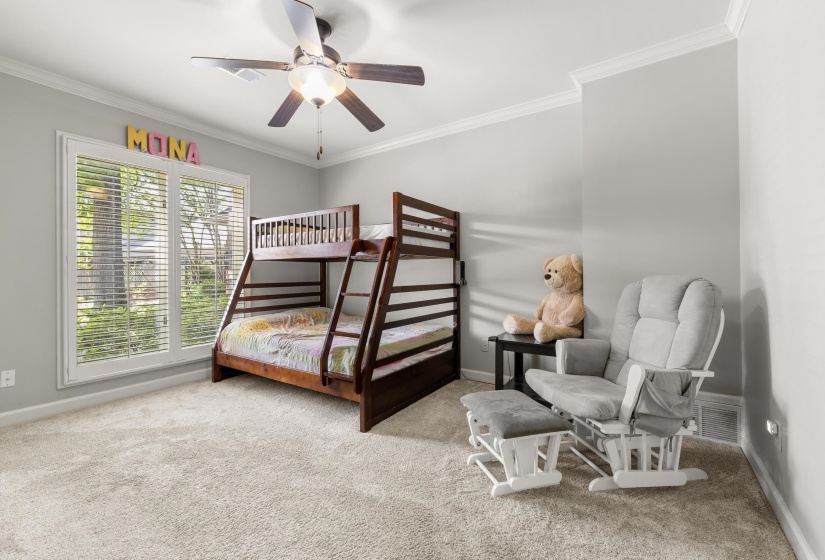 Spacious room featuring light gray wall paint, crown molding, a ceiling fan with light fixture, large windows with blinds, and light-colored carpet flooring