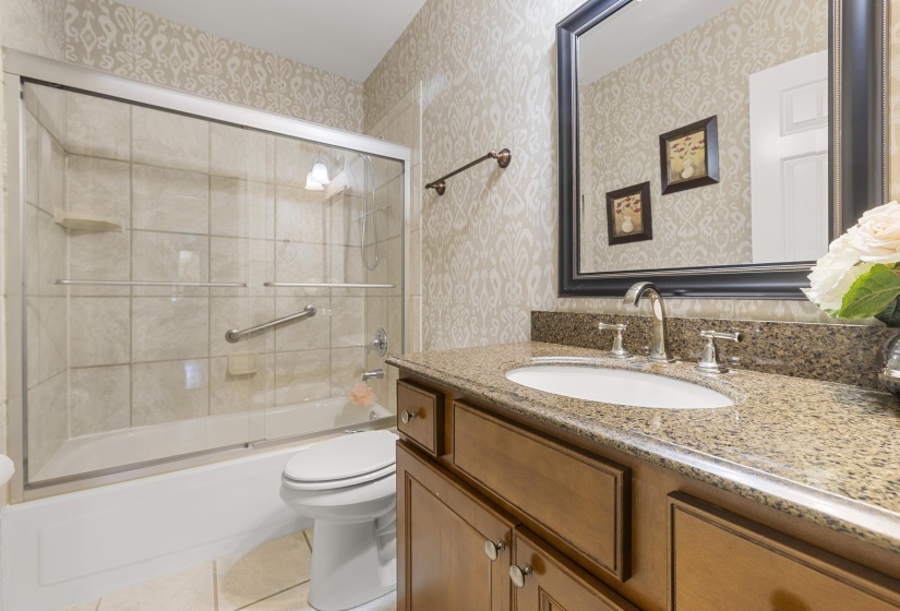 Bathroom featuring a vanity with a granite-style countertop, undermount sink, and wood-finish cabinetry