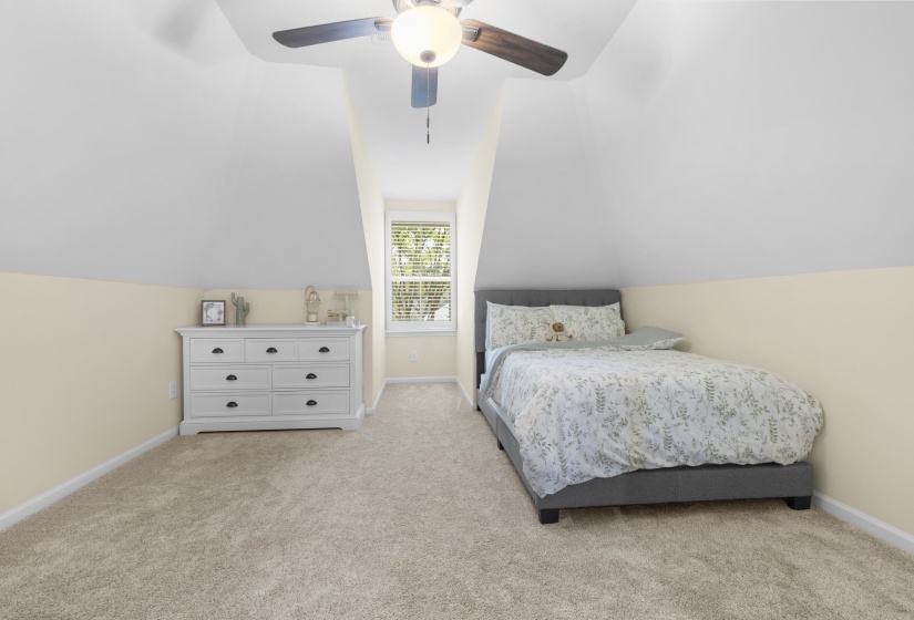 Carpeted room with sloped ceilings and light beige walls