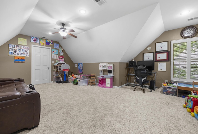 Carpeted bonus room featuring a window with plantation shutters, a ceiling fan with light fixture, recessed lighting, and a white paneled door
