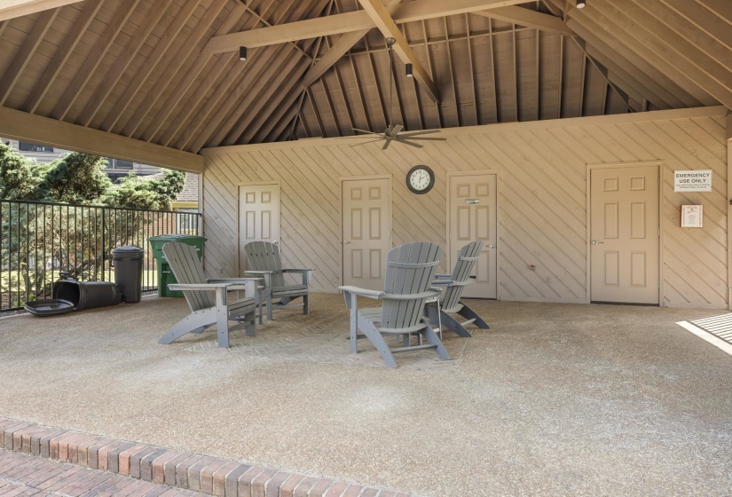 Covered outdoor patio area featuring a slatted ceiling with exposed beams, textured wall paneling, and a ceiling fan