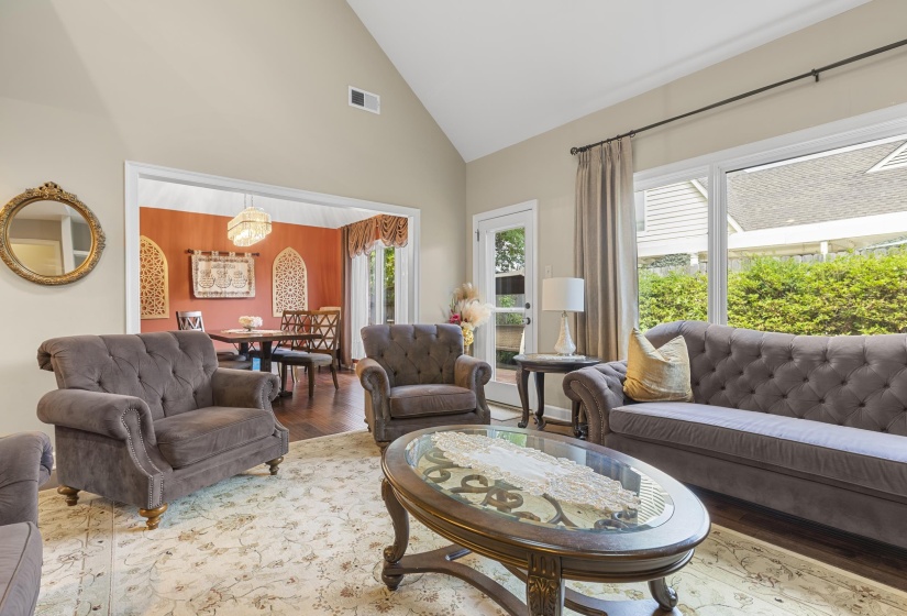 Vaulted ceiling living area featuring a large window, a glass-paned exterior door, and a wide entryway