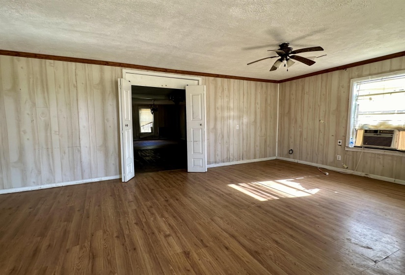 Unfurnished bedroom with ceiling fan, cooling unit, wood-type flooring, ornamental molding, and a textured ceiling