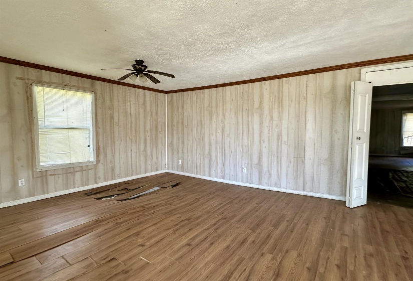 Empty room featuring hardwood / wood-style flooring, ornamental molding, a textured ceiling, and a wealth of natural light