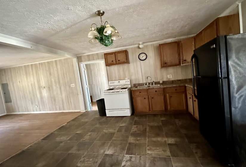 Kitchen featuring sink, pendant lighting, a textured ceiling, black refrigerator, and electric stove
