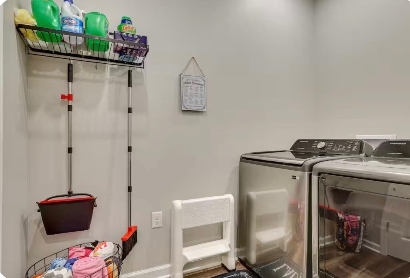Laundry area featuring light gray walls, wood-finish flooring, and built-in overhead shelving