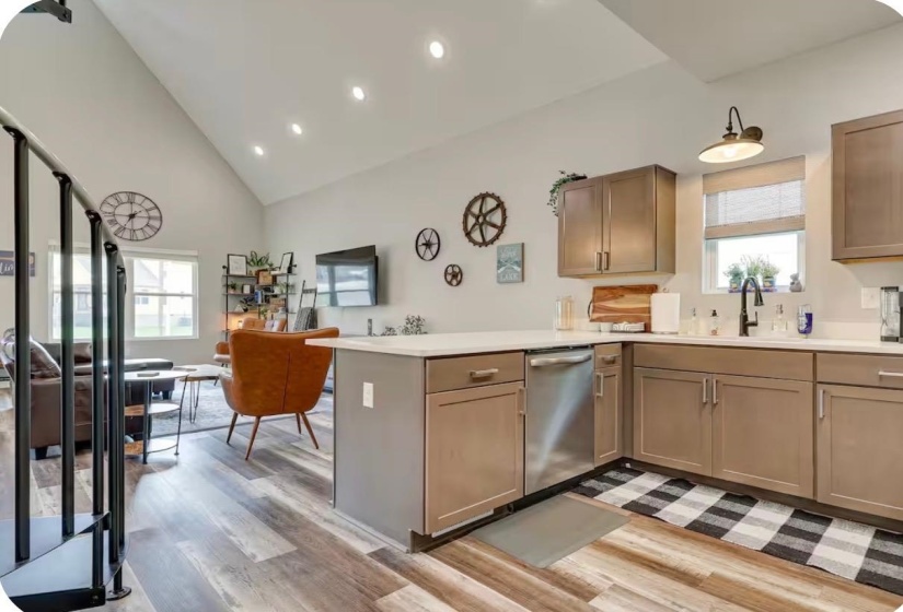 Kitchen featuring a peninsula island, stainless steel dishwasher, L-shaped cabinetry, and light-toned countertops