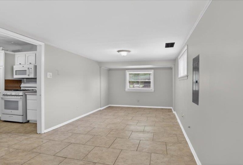 Spacious room featuring neutral tile flooring, light gray walls, and a white ceiling with crown molding