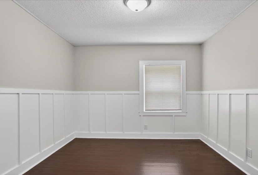 Room featuring dark wood-finish flooring and white board and batten wall paneling