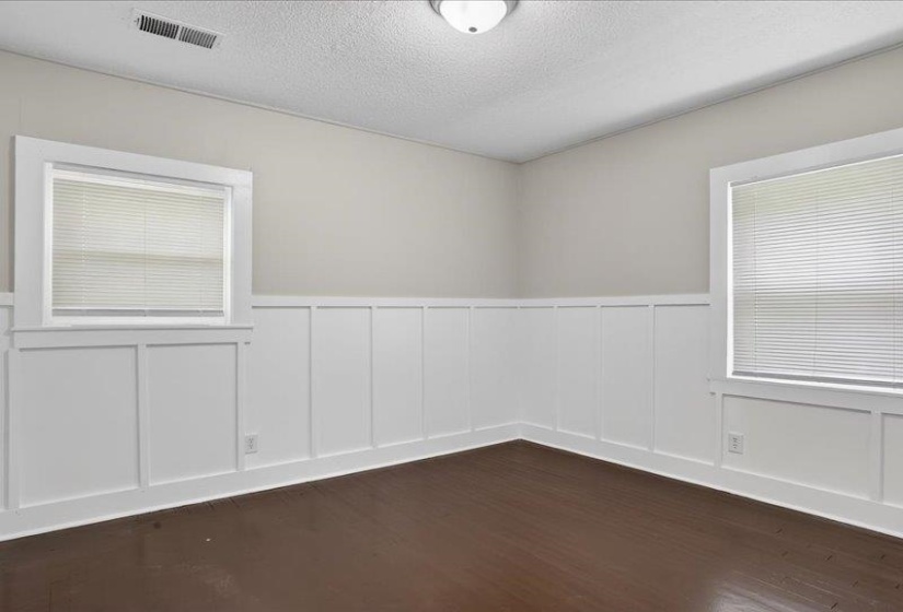 Interior room featuring dark wood-finish flooring, white paneled wainscoting, and light neutral wall paint