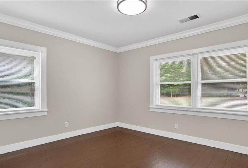 Room with light neutral walls, dark wood-finish flooring, white crown molding, and white baseboards