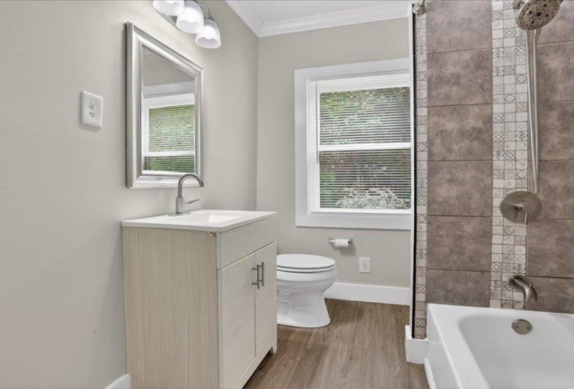 Bathroom featuring a white vanity with integrated sink, chrome faucet, framed mirror, and three-light fixture