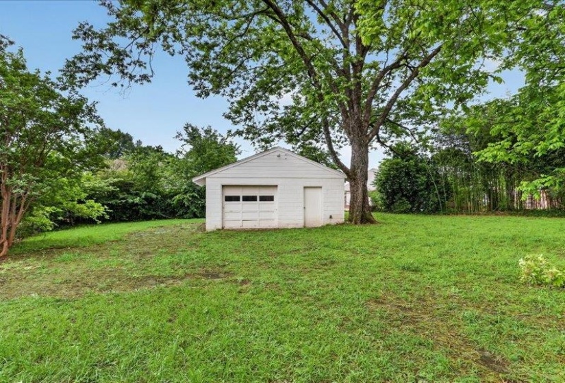 Detached white garage with a single bay door and side entry