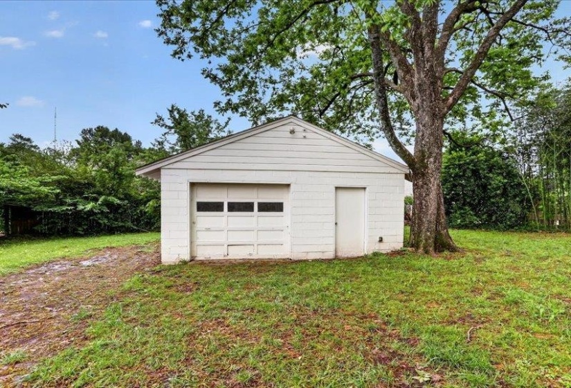 Detached white garage with a single vehicle bay and separate side entry door