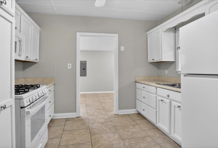 Kitchen featuring white cabinetry, light-toned countertops, a white gas range, and a white refrigerator
