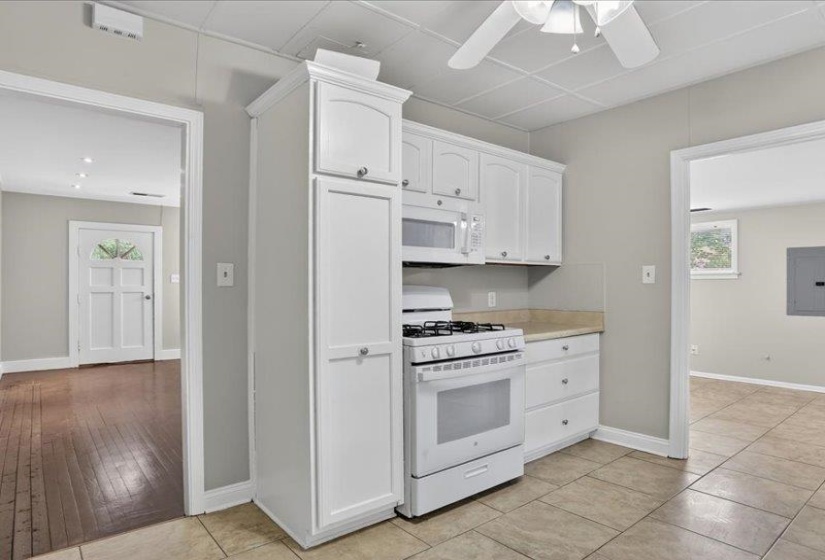 Kitchenette featuring white cabinetry, a built-in microwave, a gas range, light-toned countertops, and tile flooring