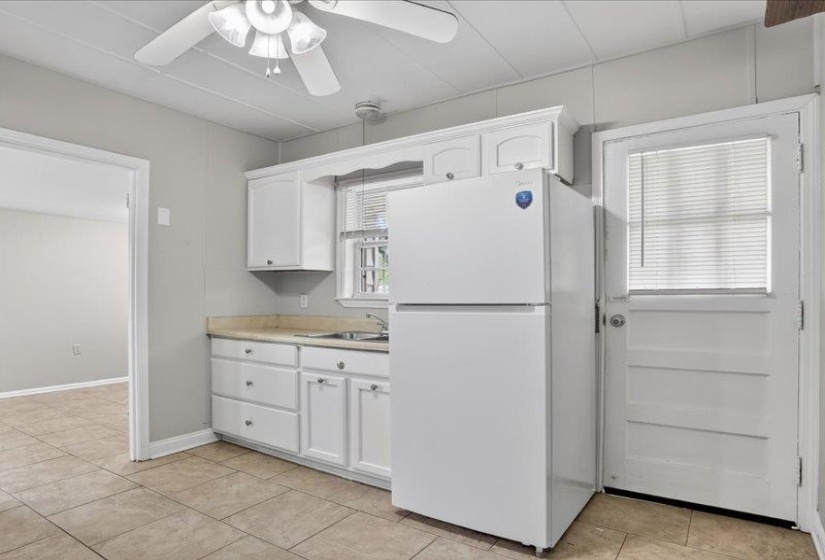 Kitchen area featuring white cabinetry, a built-in sink, and a white refrigerator