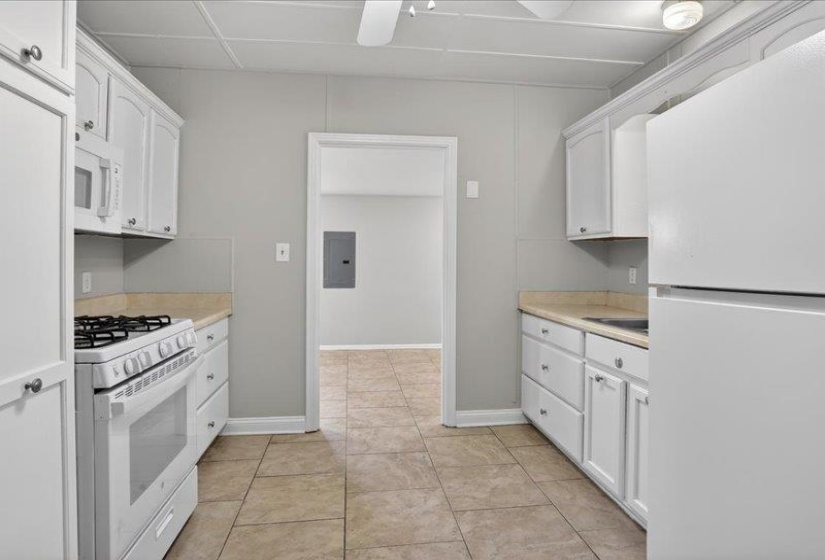 Kitchen featuring white cabinetry with brushed nickel hardware, laminate countertops, tile flooring, and a white gas range