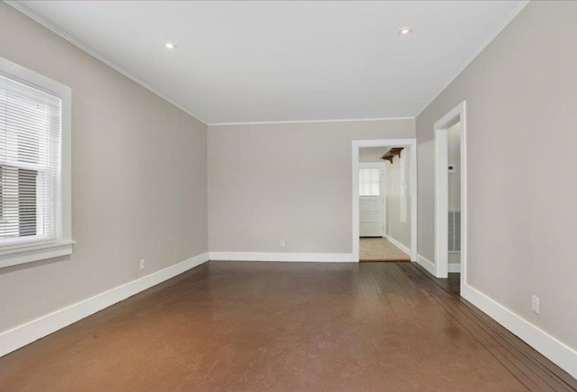Spacious room featuring rich wood-finish flooring, neutral wall tones, and bright white trim