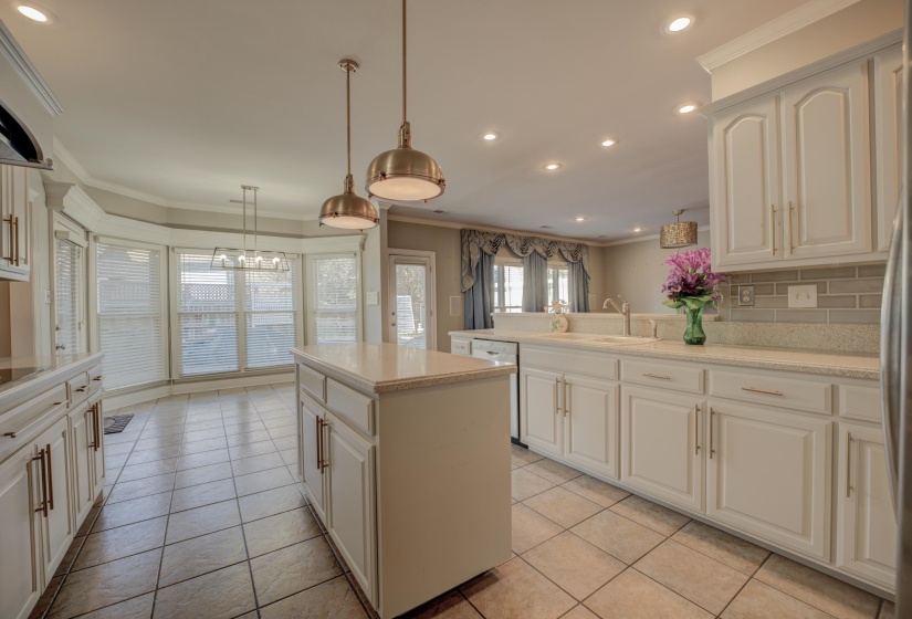 Kitchen with tasteful backsplash, ornamental molding, sink, pendant lighting, and light tile patterned floors