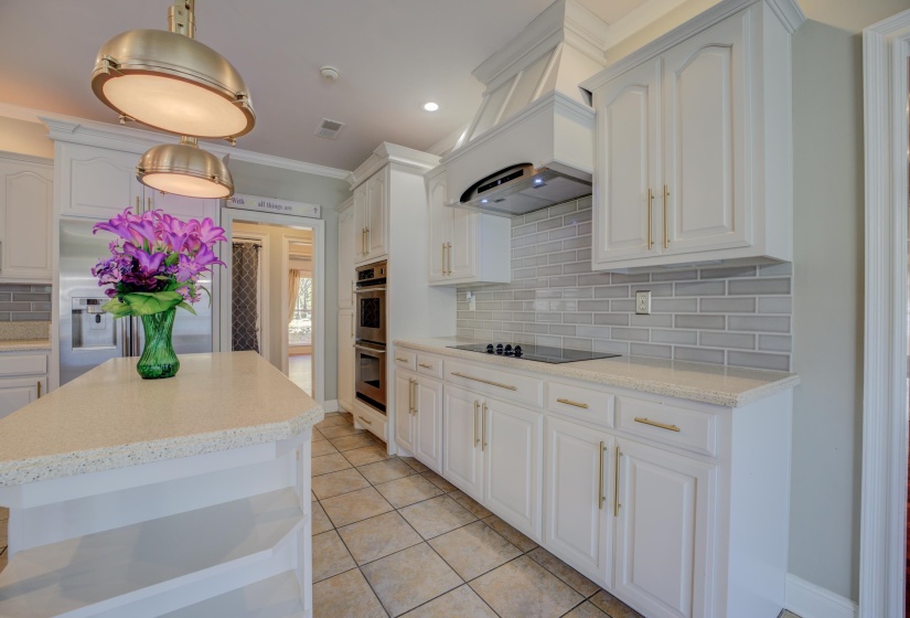 Kitchen featuring white cabinetry, stainless steel appliances, pendant lighting, decorative backsplash, and light tile patterned flooring