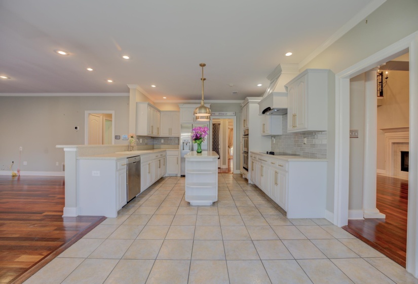Kitchen with kitchen peninsula, light wood-type flooring, tasteful backsplash, dishwasher, and hanging light fixtures