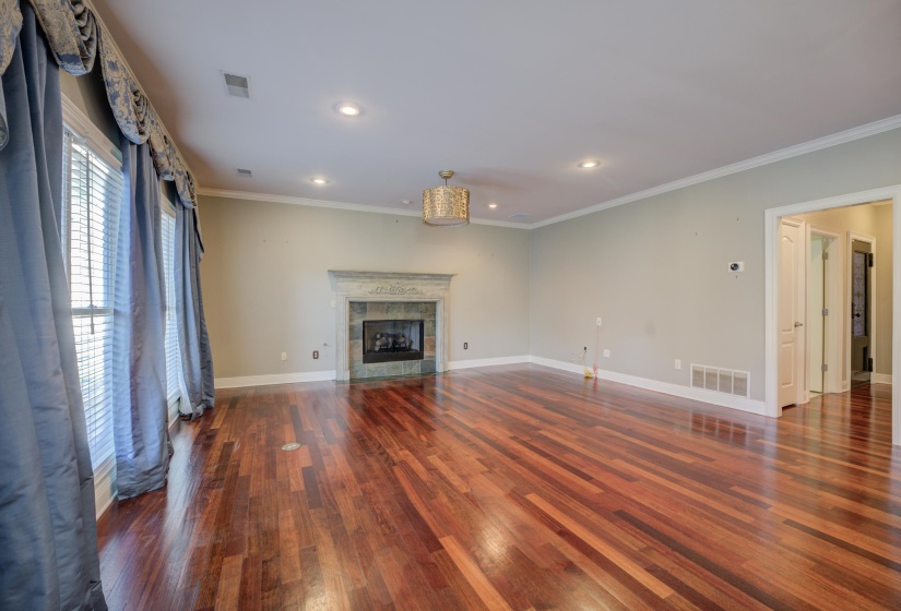 Unfurnished living room with ornamental molding, dark wood-type flooring, and a tiled fireplace